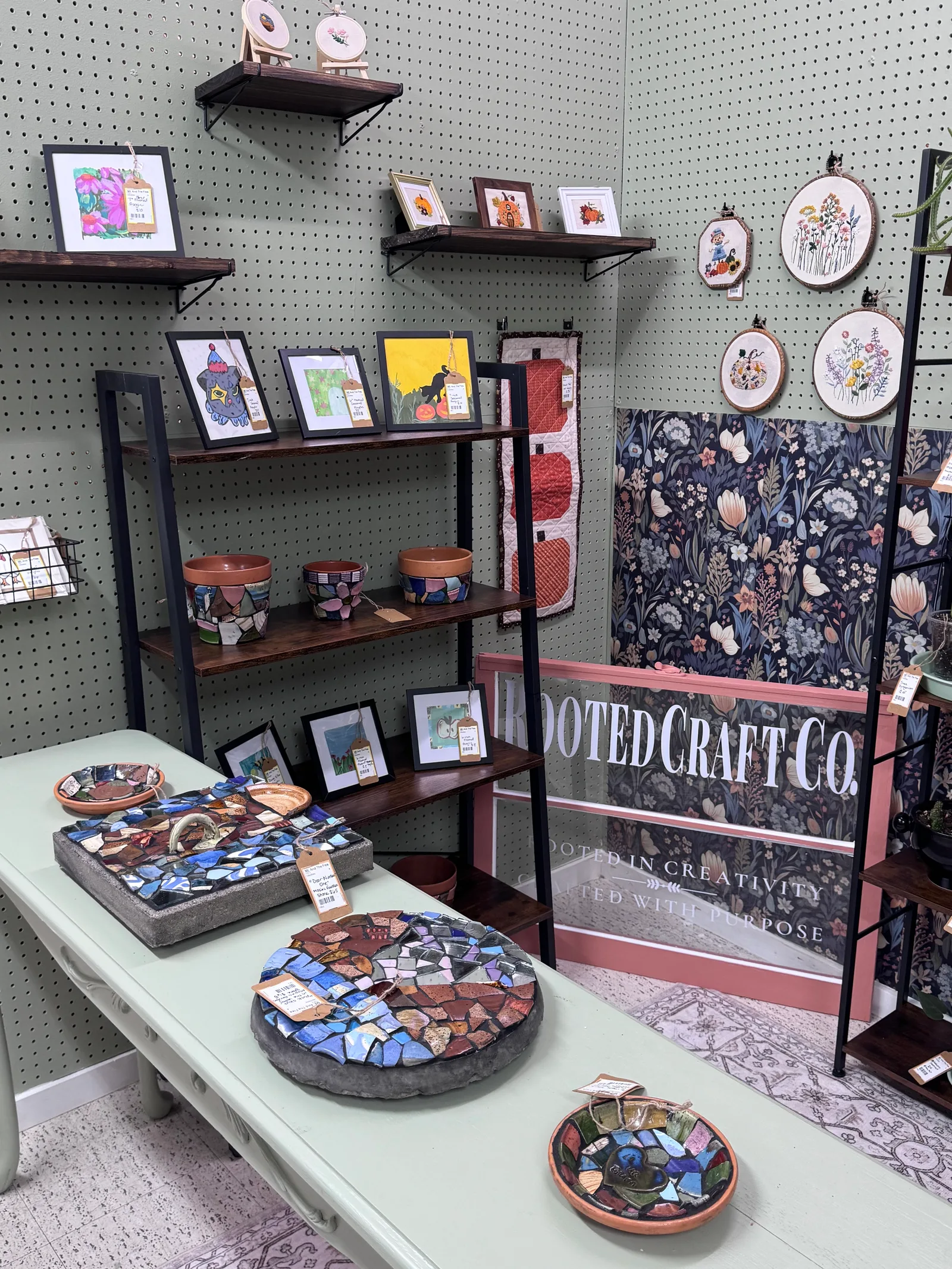 Original drawings, mosaics, and embroidery displayed at the Rooted Craft Co booth